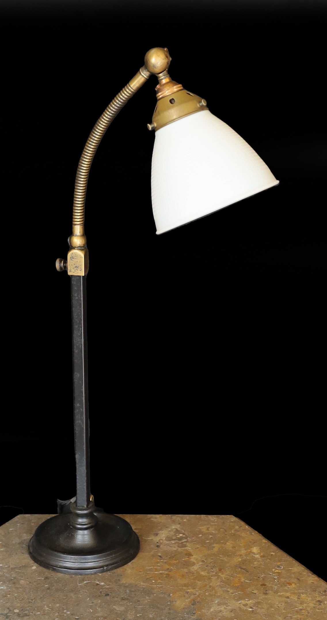 A 1930s English brass wrought iron and cast iron adjustable desk lamp with moulded opaque glass shade, height 66cm
